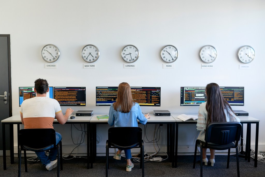 3 students in a market finance computer room